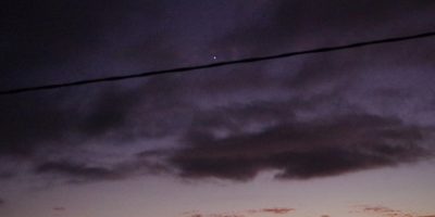 Venus peaking through a gap in dark clouds with the remains of sunset below